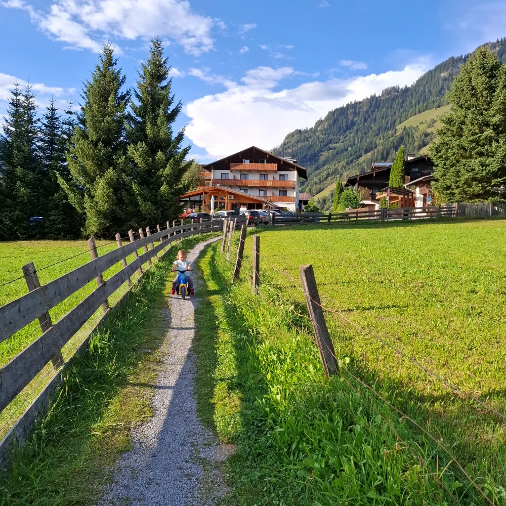 Alpesi panoráma zöld legelőkkel és egy hangulatos hegyi hotellel